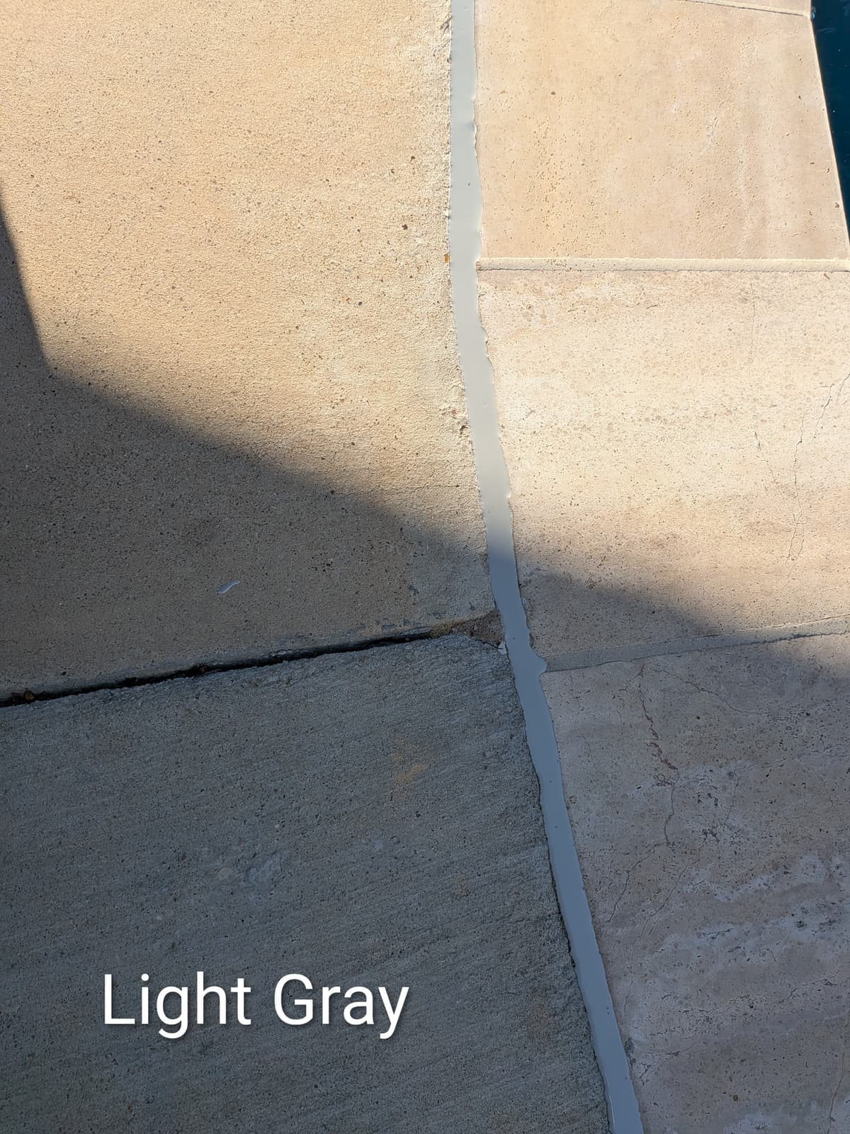 Light Gray pool mastic sealant color example, a Dallas Mastic custom blend of Sika Gray, on travertine pavers and concrete — smooth finish