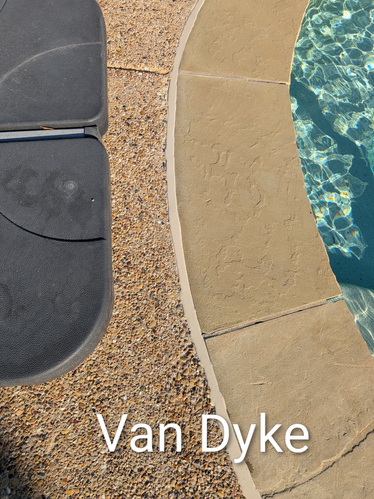 Sika Van Dyke pool mastic sealant color example on flagstone coping with exposed aggregate deck — smooth finish