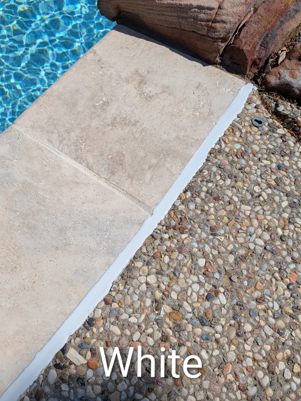 Sika White pool mastic sealant color example on travertine coping with exposed aggregate deck — smooth finish
