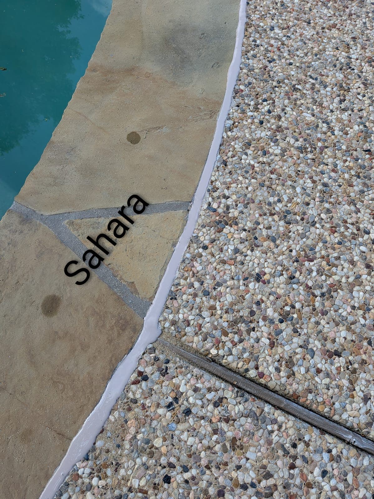 Sika Sahara pool mastic sealant color example on flagstone coping with pebble aggregate deck — smooth finish